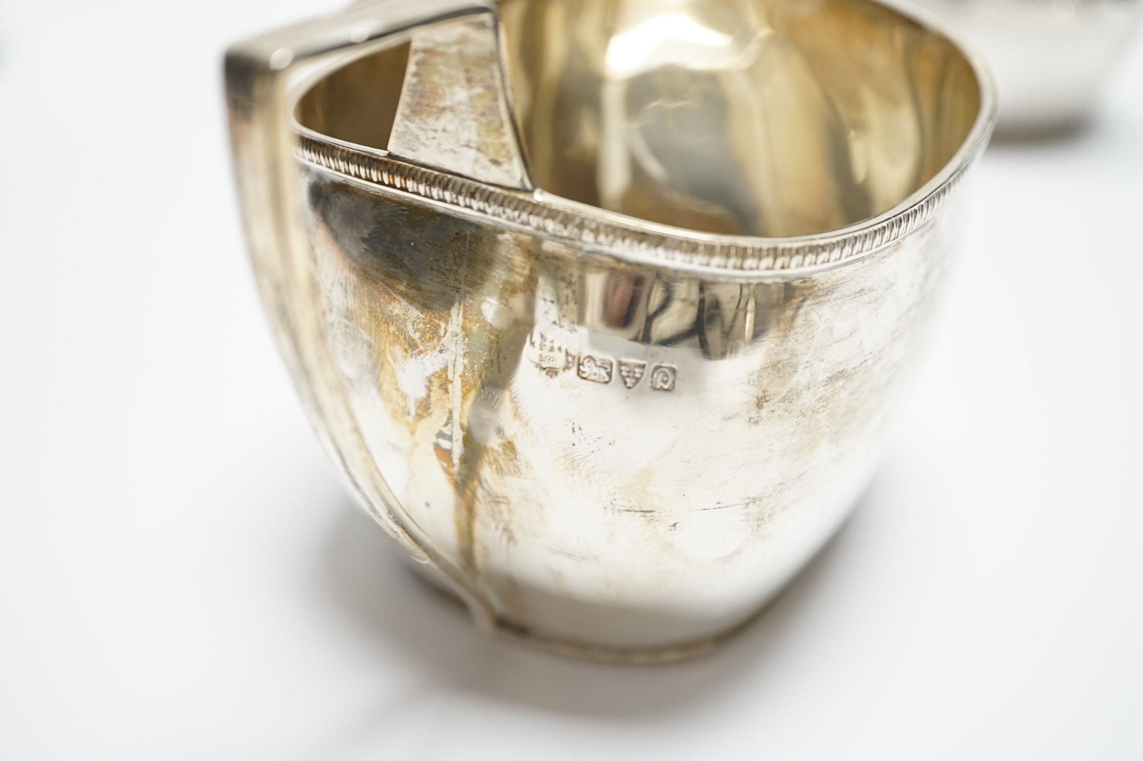 A George III engraved silver cream jug, London, 1808, height 82m, a George V silver cream jug and matching sugar bowl, and a George V silver five bar toast rack, 15.4oz.